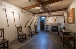 Eingangshalle mit Familienwappen über dem Kamin und Waffensammlung