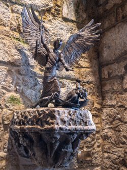 Der Erzengel Michael reicht dem besiegten Luzifer die Hand zur Versöhnung. Bronzestatue von Lyn Constable Maxwell, 1989